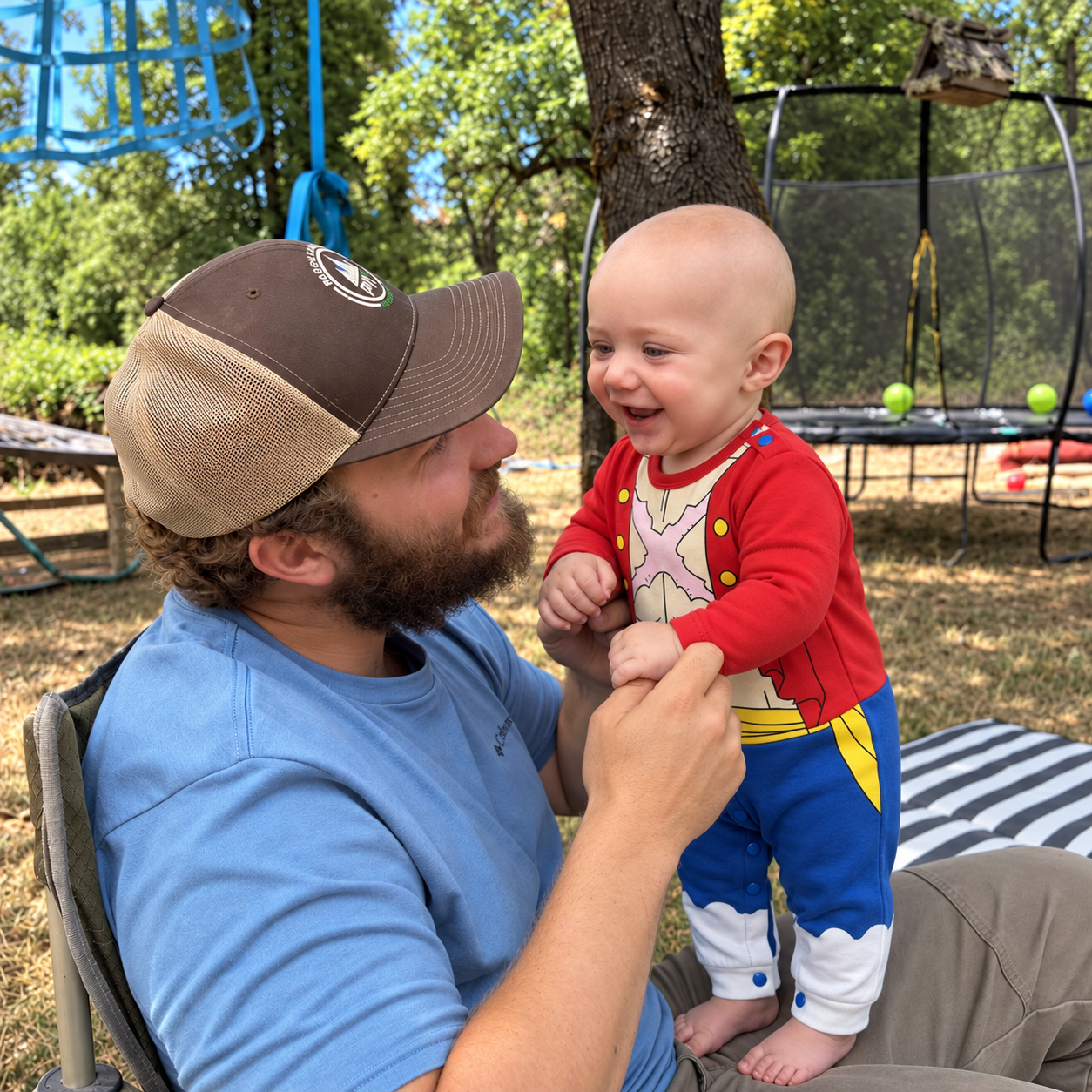 Dad holding a smiling baby in a Little Luffy romper outdoors